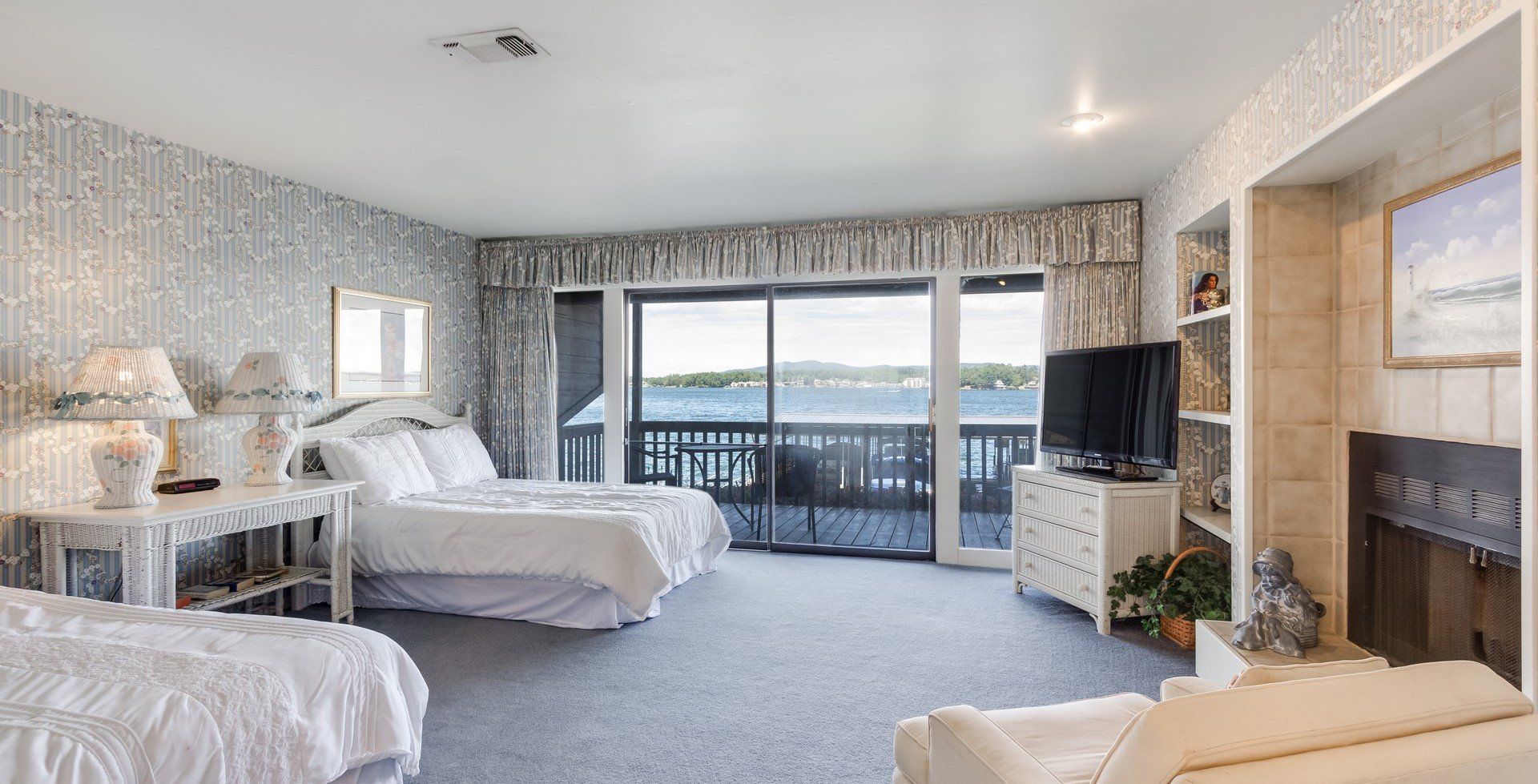 A hotel room with two beds , a couch , a television and a fireplace.