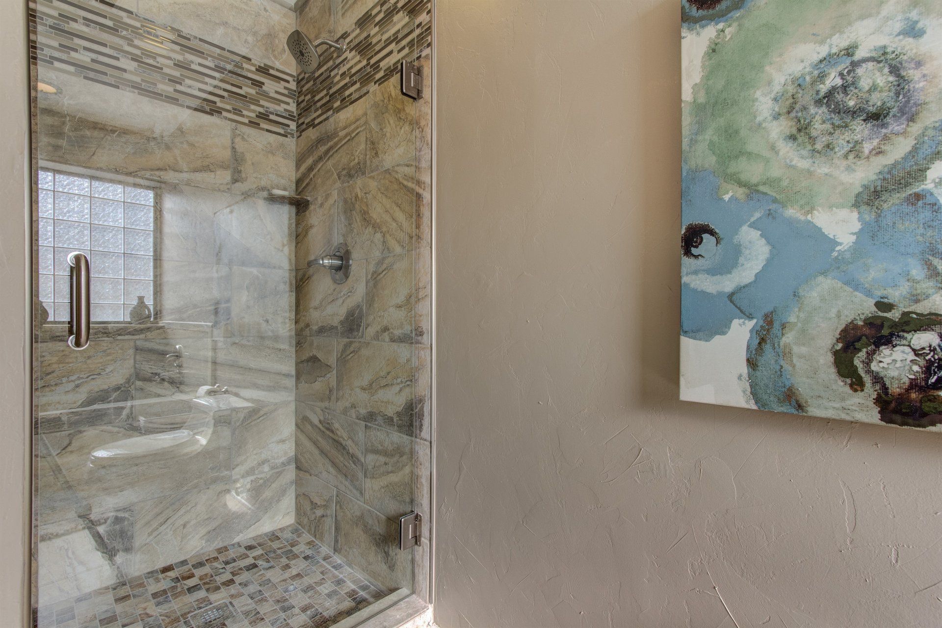 A bathroom with a walk in shower and a painting on the wall.