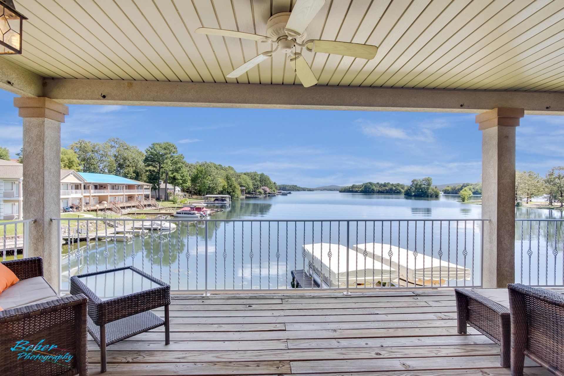 A balcony overlooking a lake with a ceiling fan