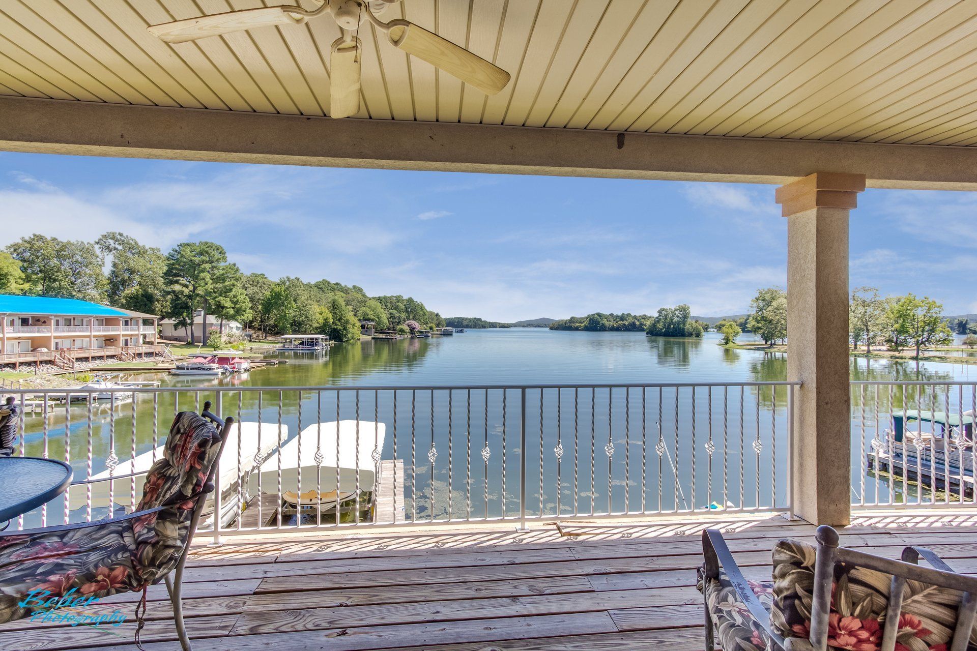 A view of a lake from a deck with a ceiling fan