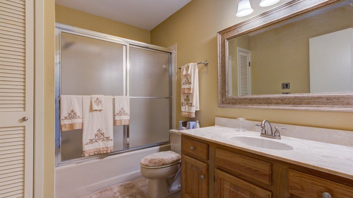 A bathroom with a toilet , sink , shower and mirror.