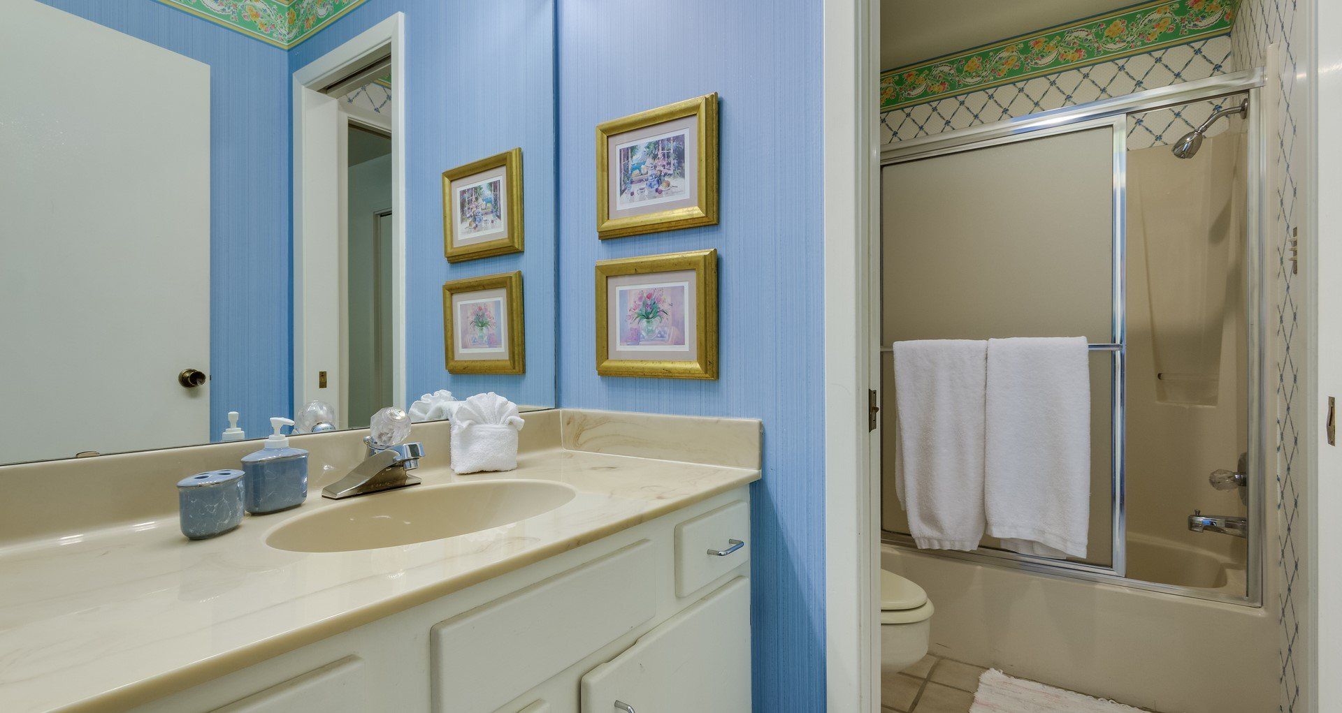 A bathroom with a sink , toilet , shower and mirror.