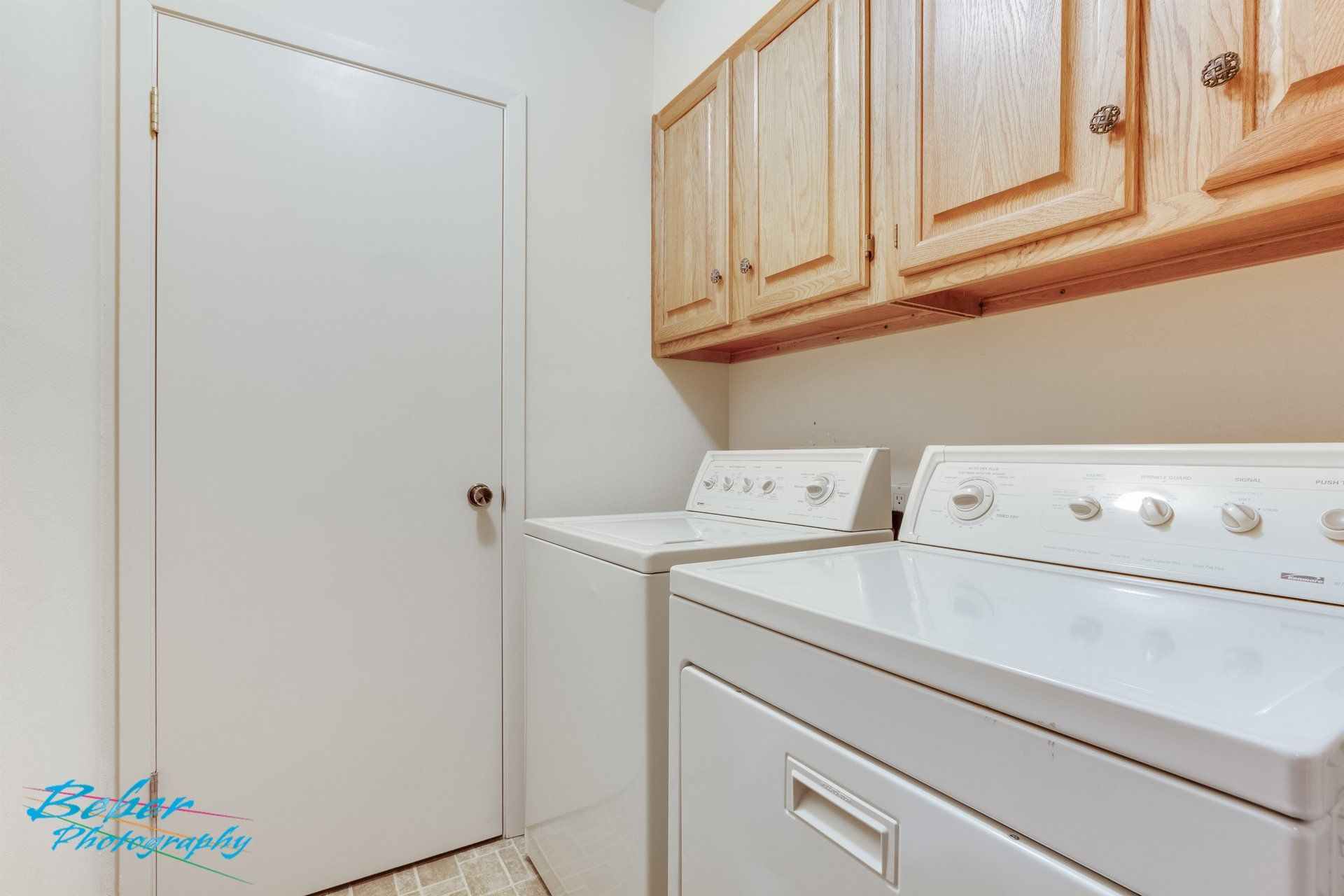 A laundry room with a washer and dryer and wooden cabinets.