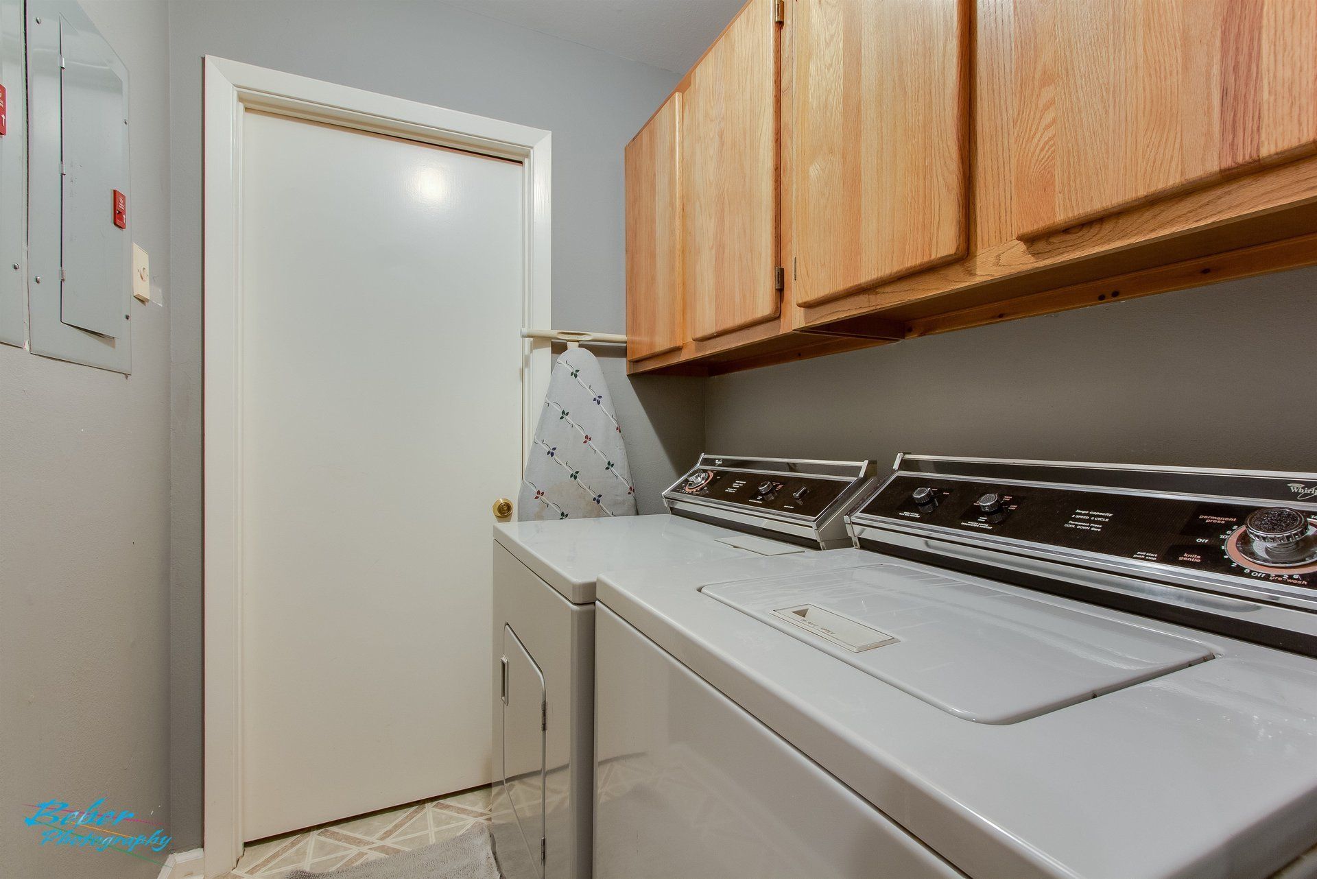 A laundry room with a washer and dryer and wooden cabinets.