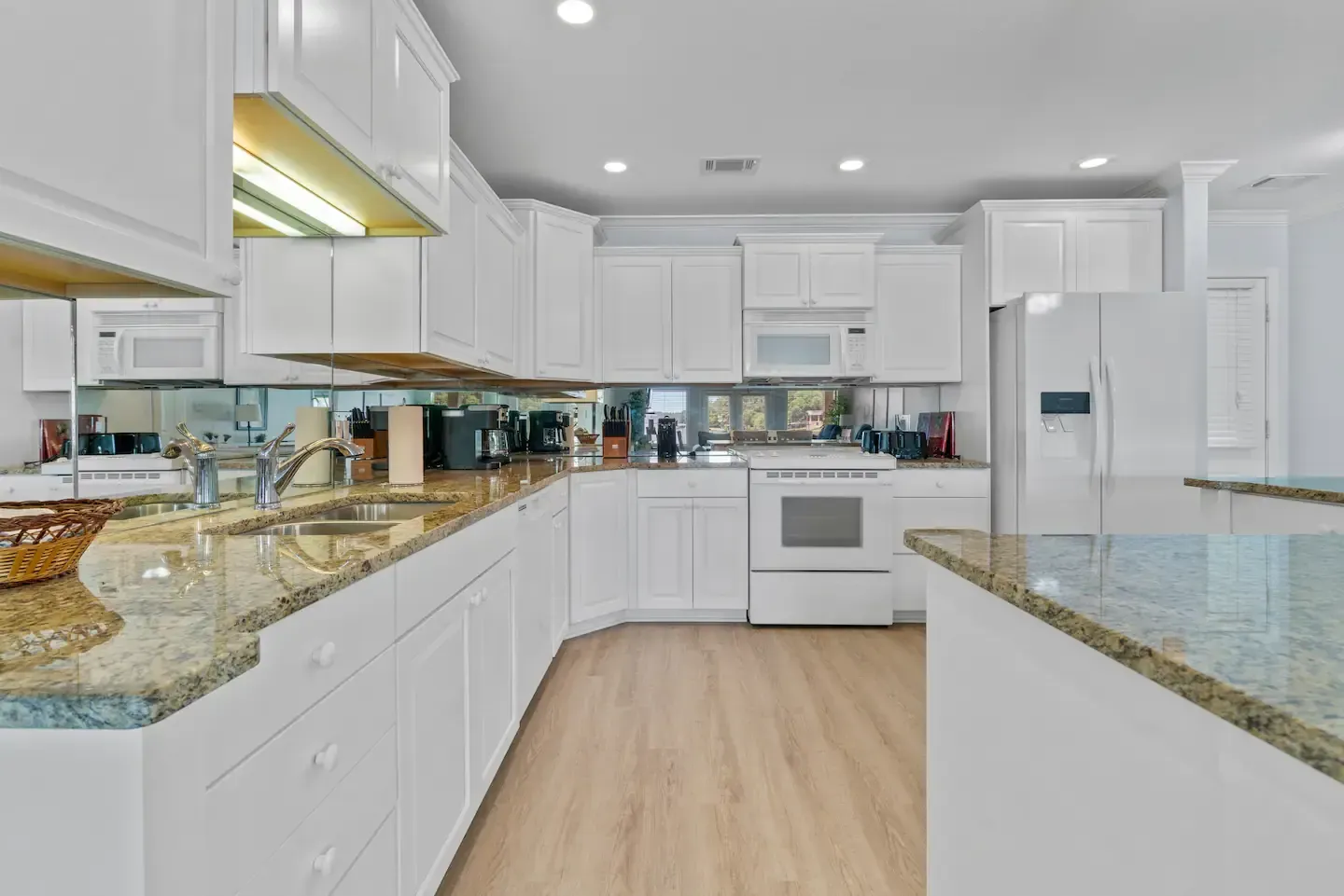 A kitchen with white cabinets and granite counter tops.