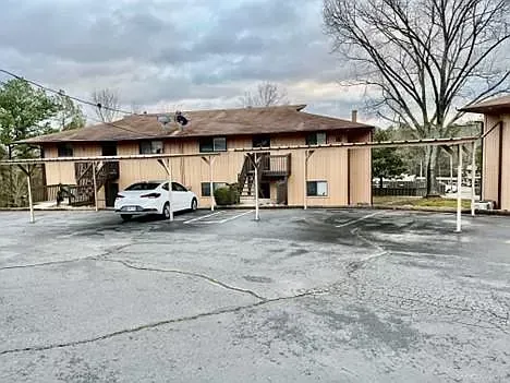 A white car is parked in a parking lot in front of a building.