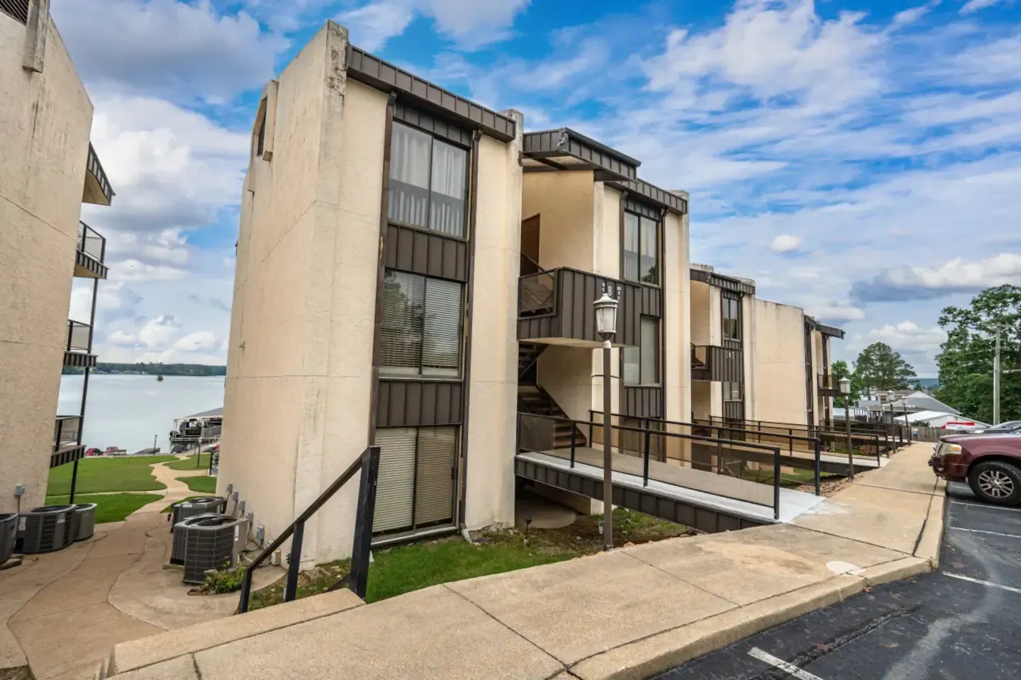 A row of apartment buildings with stairs leading up to them and a car parked in front of them.