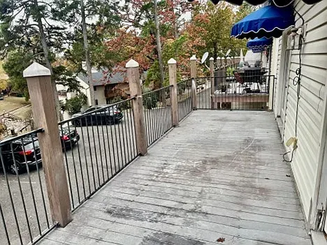 A large wooden deck with a metal railing and blue awnings.