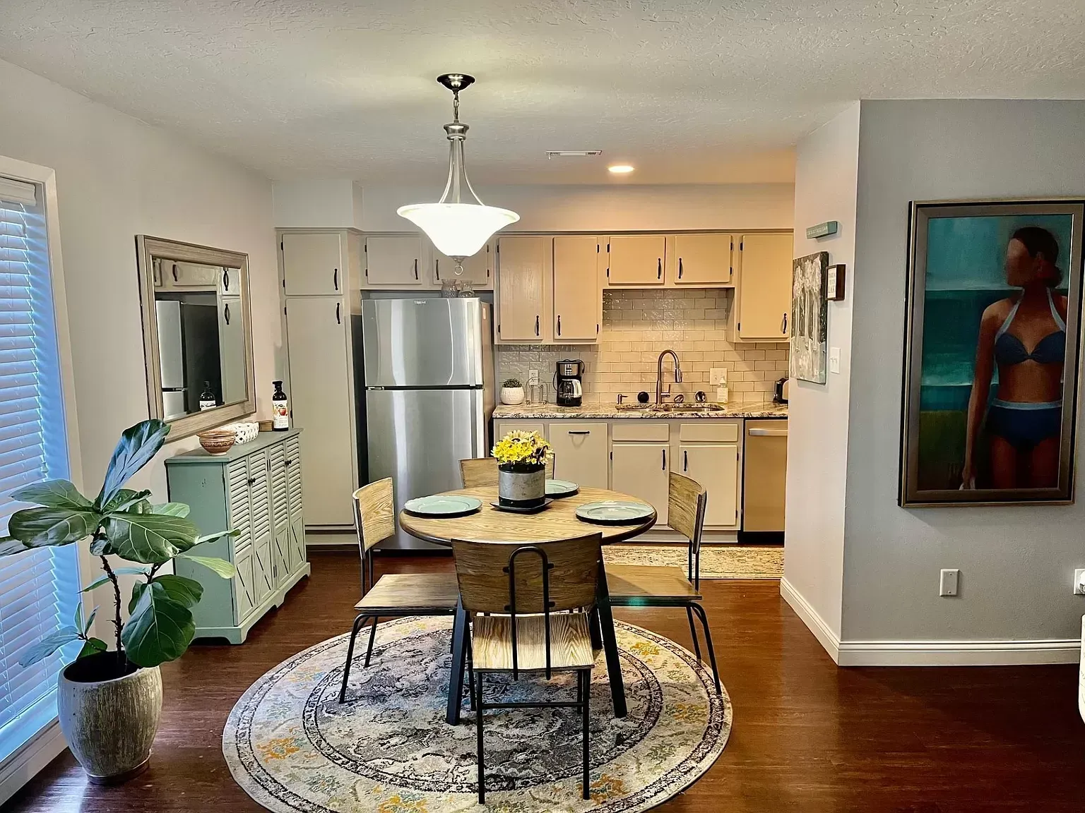 A kitchen and dining room in a house with a round table and chairs.