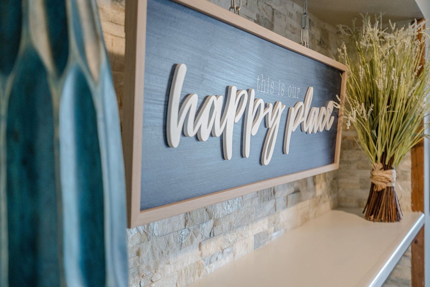 A sign that says `` happy place '' is hanging on a brick wall.