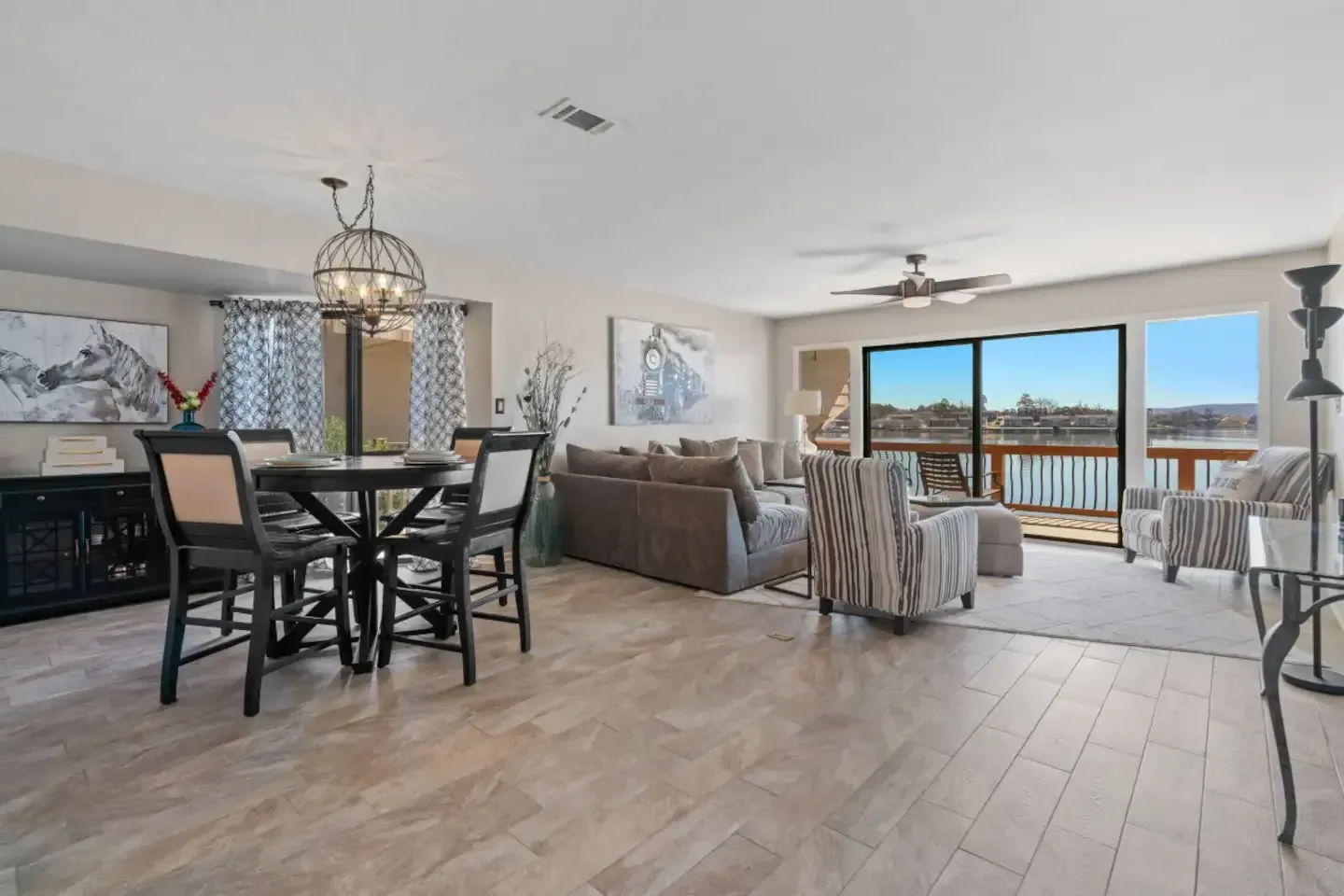 A living room with a couch , chairs , a table and a view of a lake.
