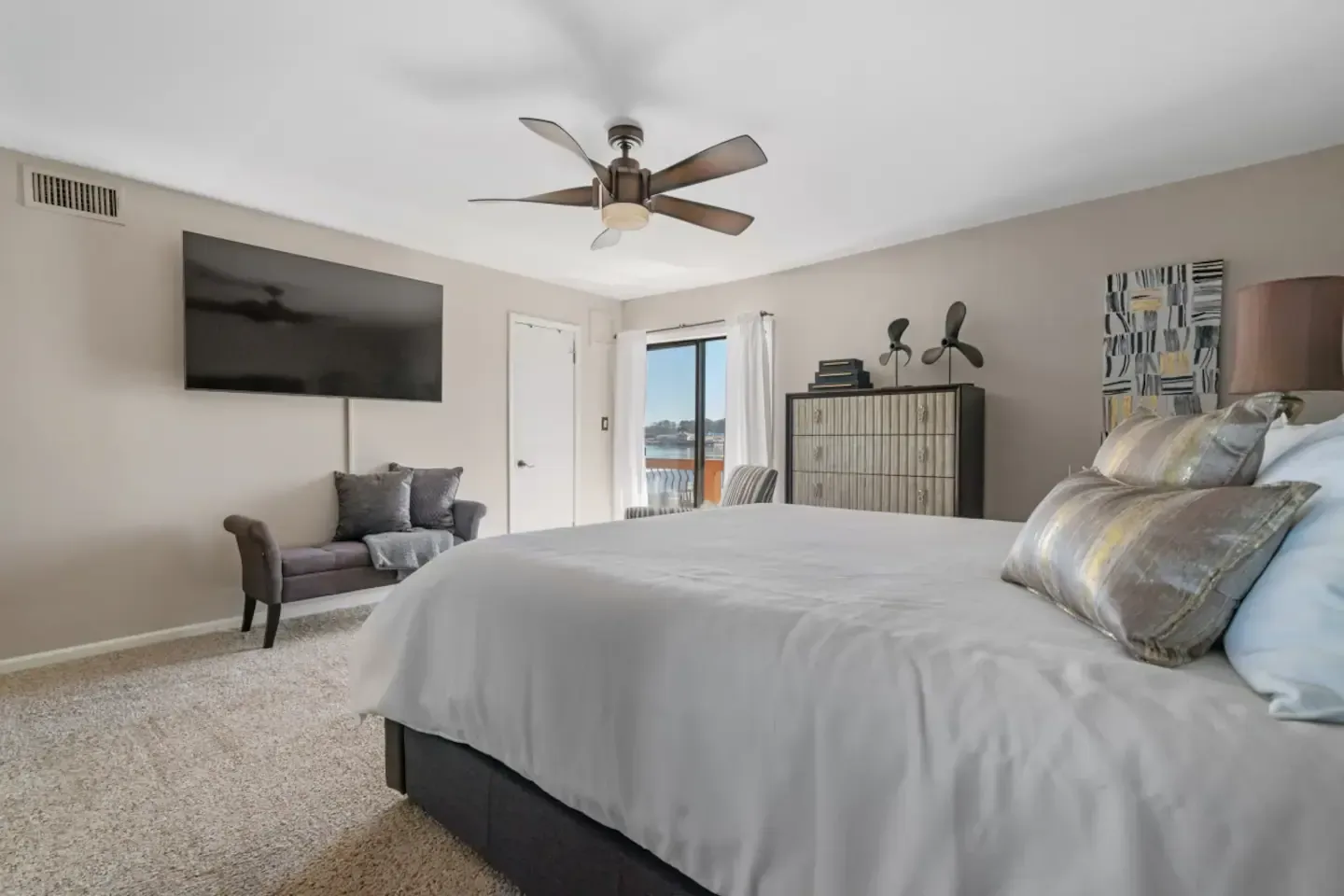 A bedroom with a king size bed , a flat screen tv , and a ceiling fan.