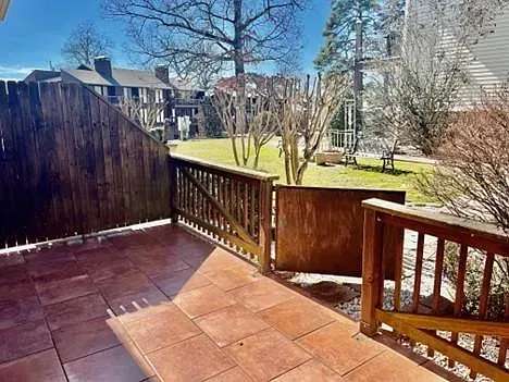 There is a patio with a wooden railing and a wooden fence.