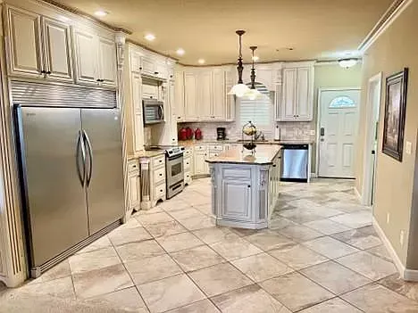 A kitchen with white cabinets , stainless steel appliances , and a tiled floor.