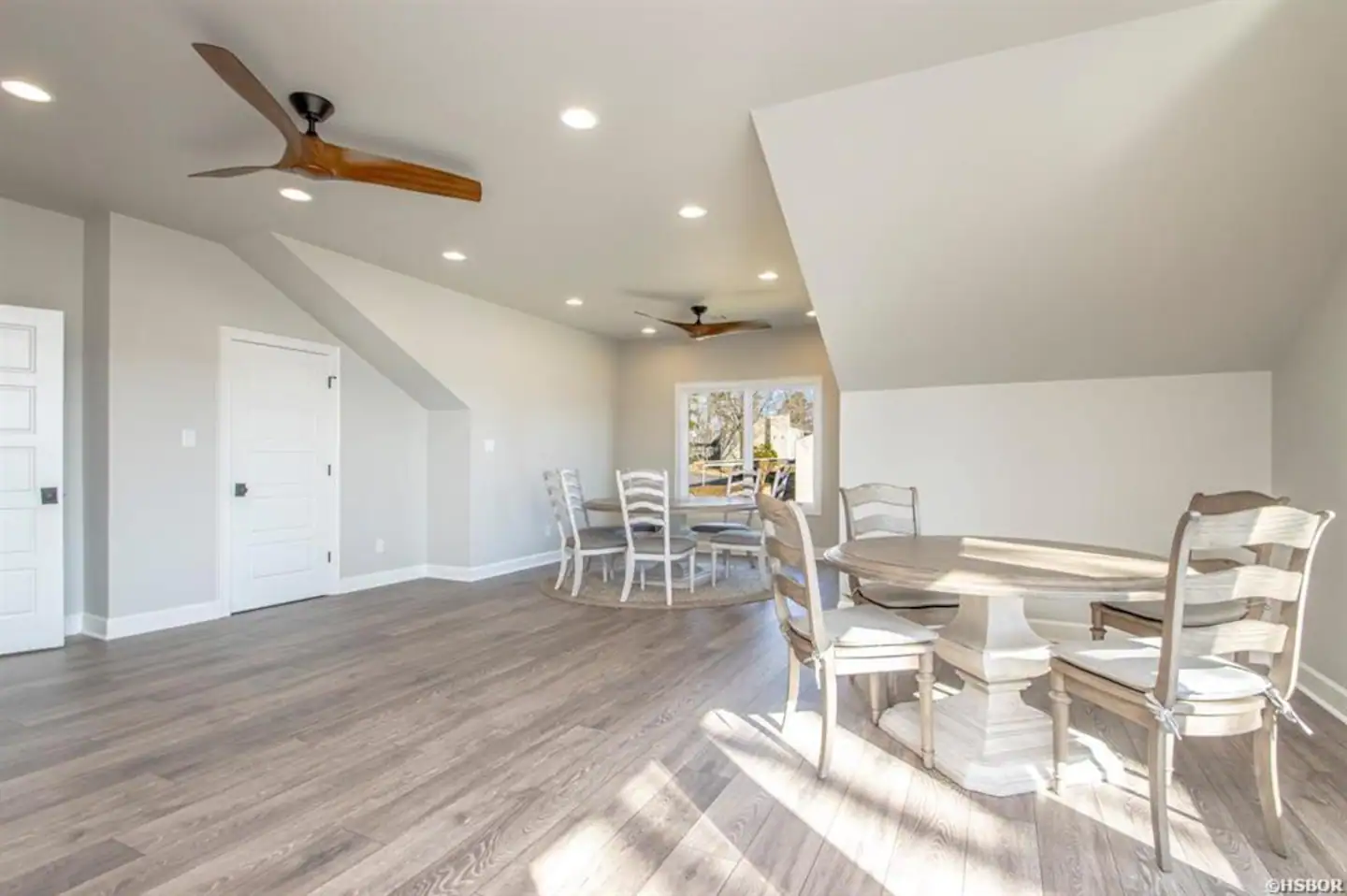 A dining room with a table and chairs and a ceiling fan.