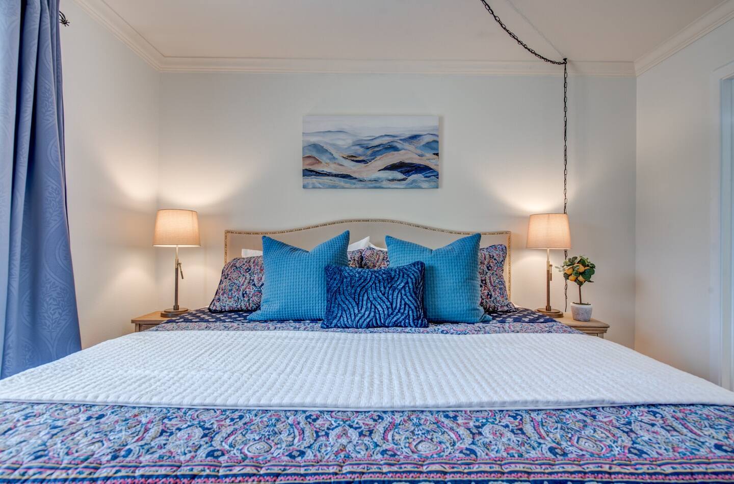 There is a painting on the wall above the bed in the bedroom.