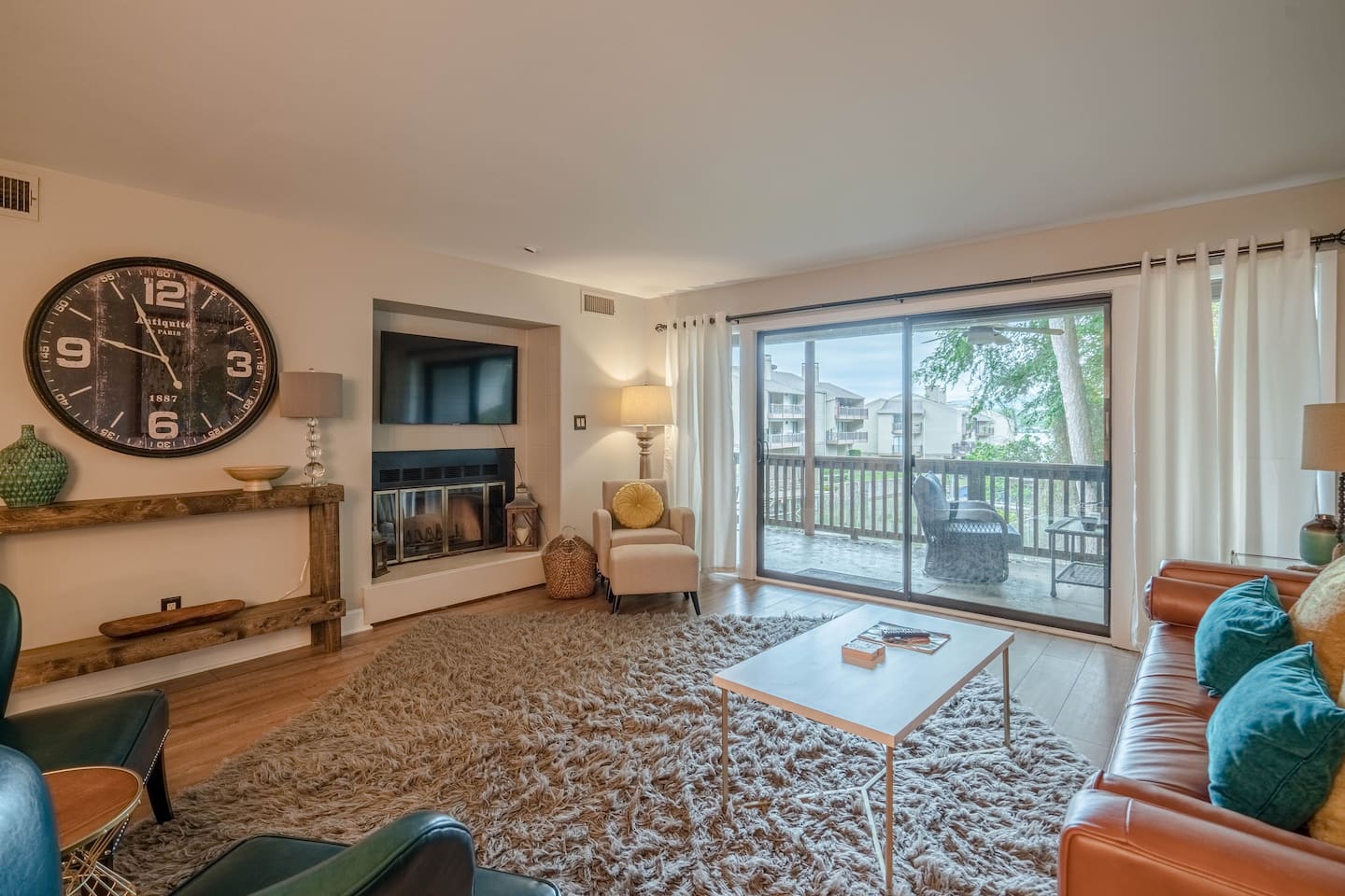 A living room with a couch , chairs , coffee table and a clock on the wall.