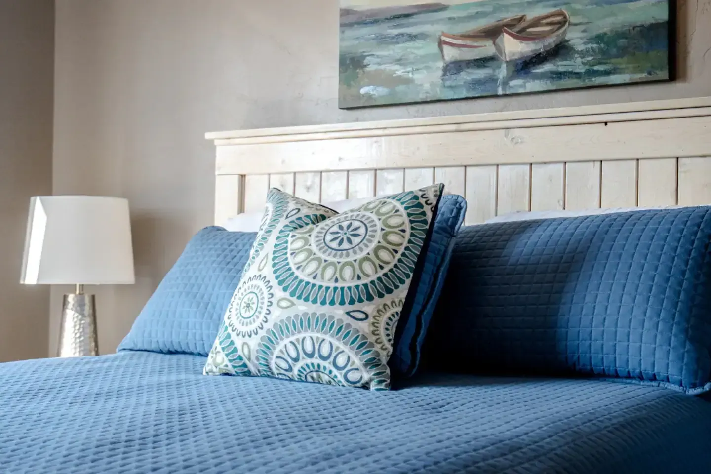 There is a painting of boats on the wall above the bed.