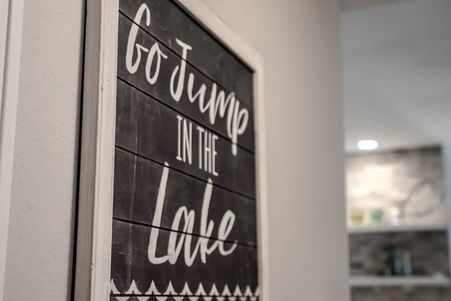 A sign that says `` go jump in the lake '' is hanging on a wall.