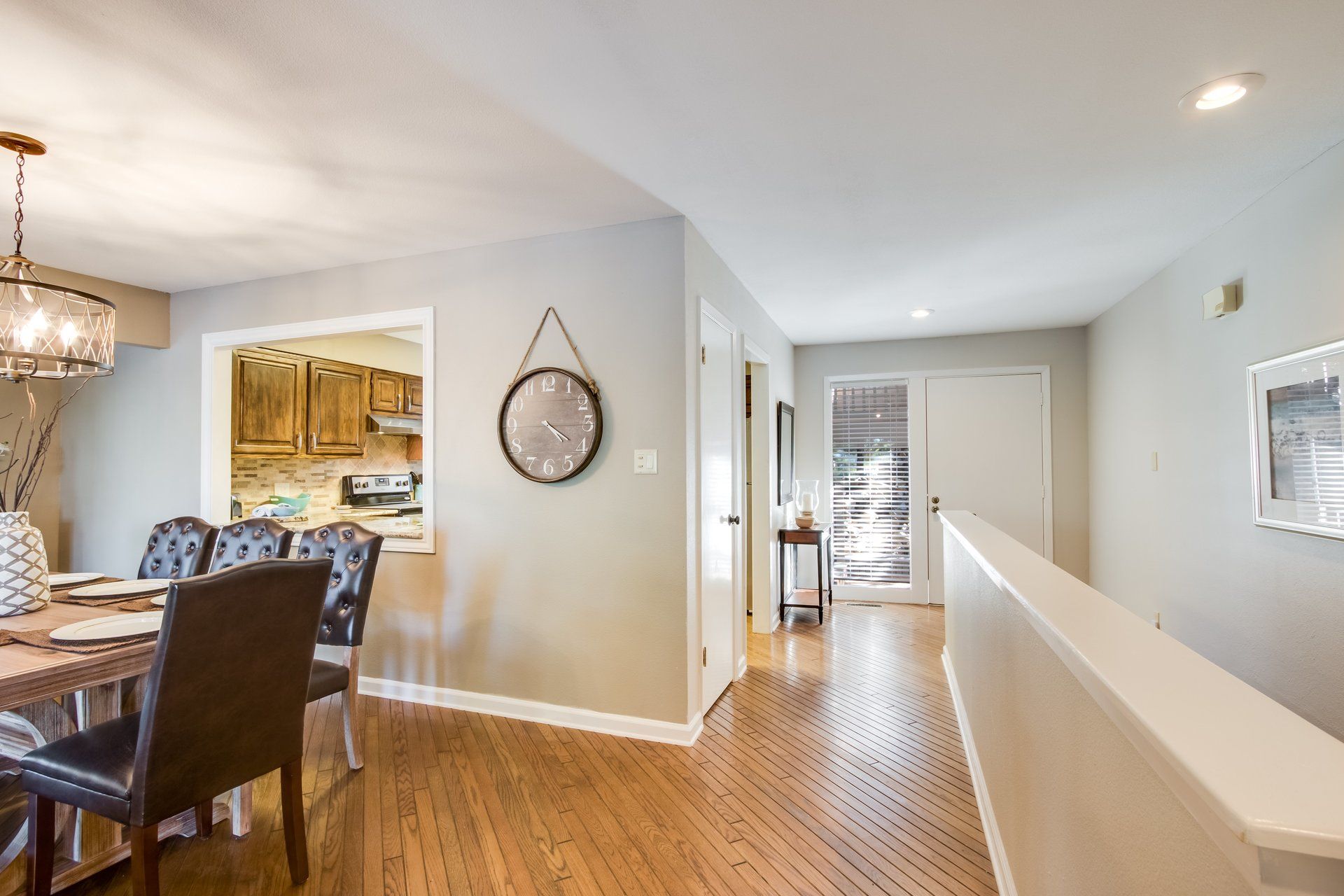 A dining room with a table and chairs and a clock on the wall.