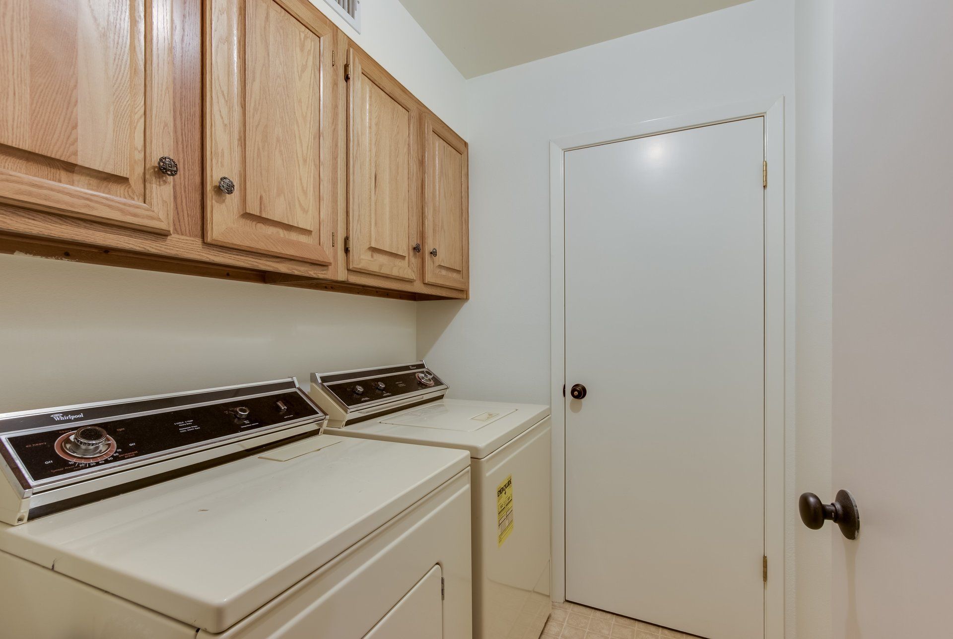 A laundry room with a washer and dryer and wooden cabinets.