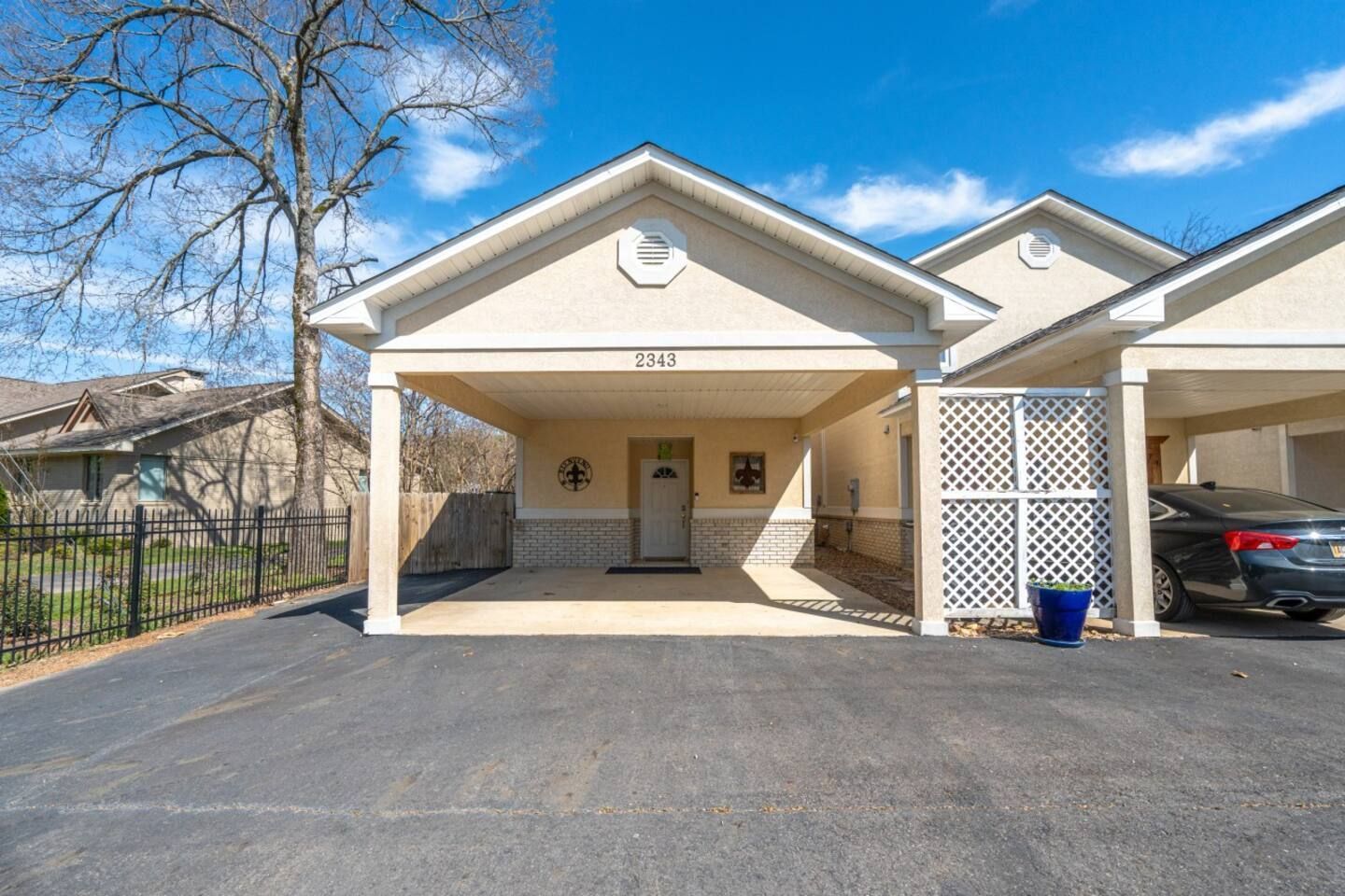 A car is parked in front of a house with a carport.