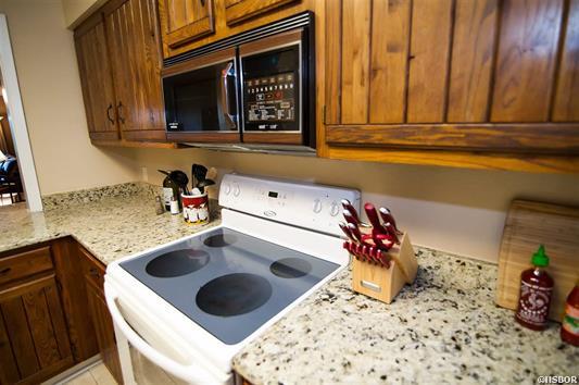 A kitchen with a stove , microwave , and cutting board.