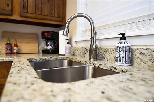 A kitchen sink with a soap dispenser on the counter.