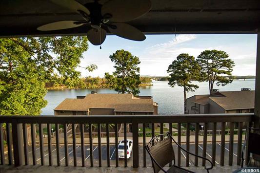 A view of a lake from a balcony with a ceiling fan