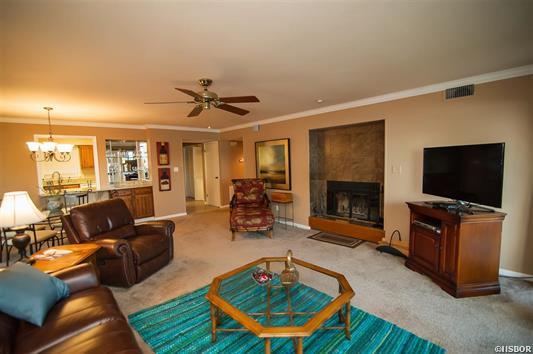A living room with a couch , chair , coffee table , television and fireplace.