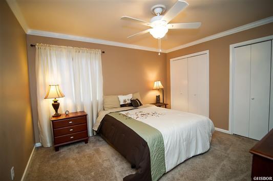 A bedroom with a bed and a ceiling fan