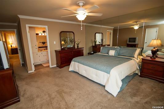A bedroom with a large bed and a ceiling fan