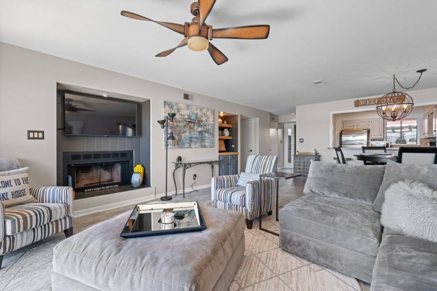 A living room with a couch , chairs , ottoman and ceiling fan.