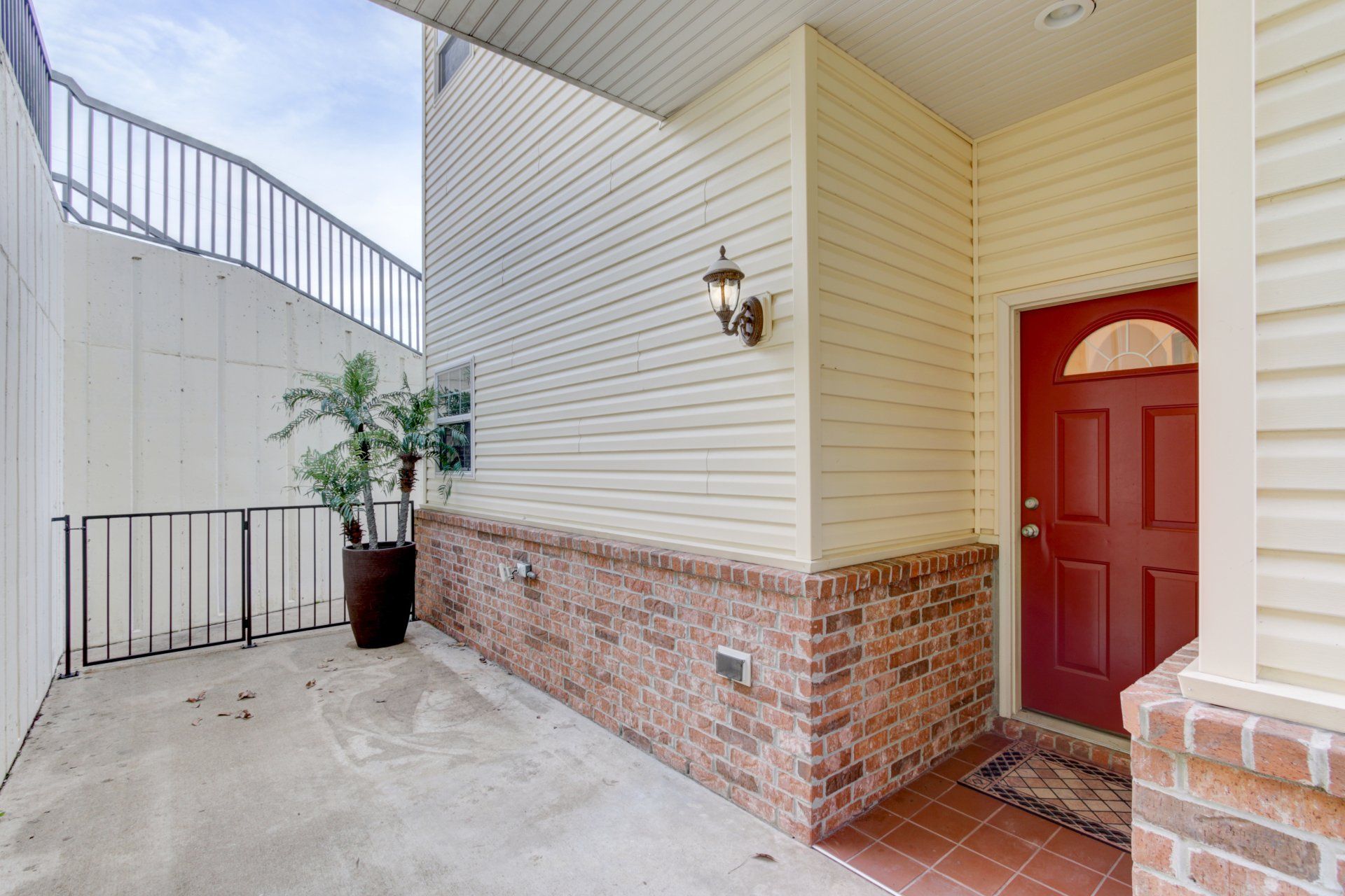 The front door of a house with a red door and a brick wall.