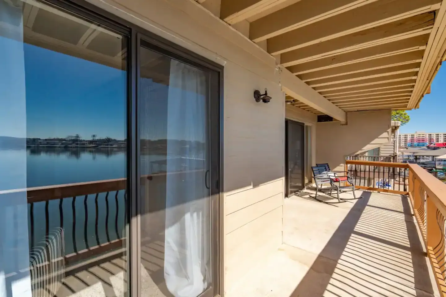 A balcony with sliding glass doors overlooking a body of water.