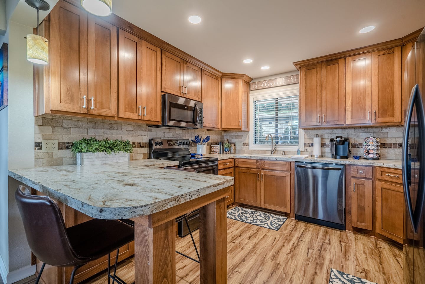 A kitchen with wooden cabinets , granite counter tops , stainless steel appliances and a large island.