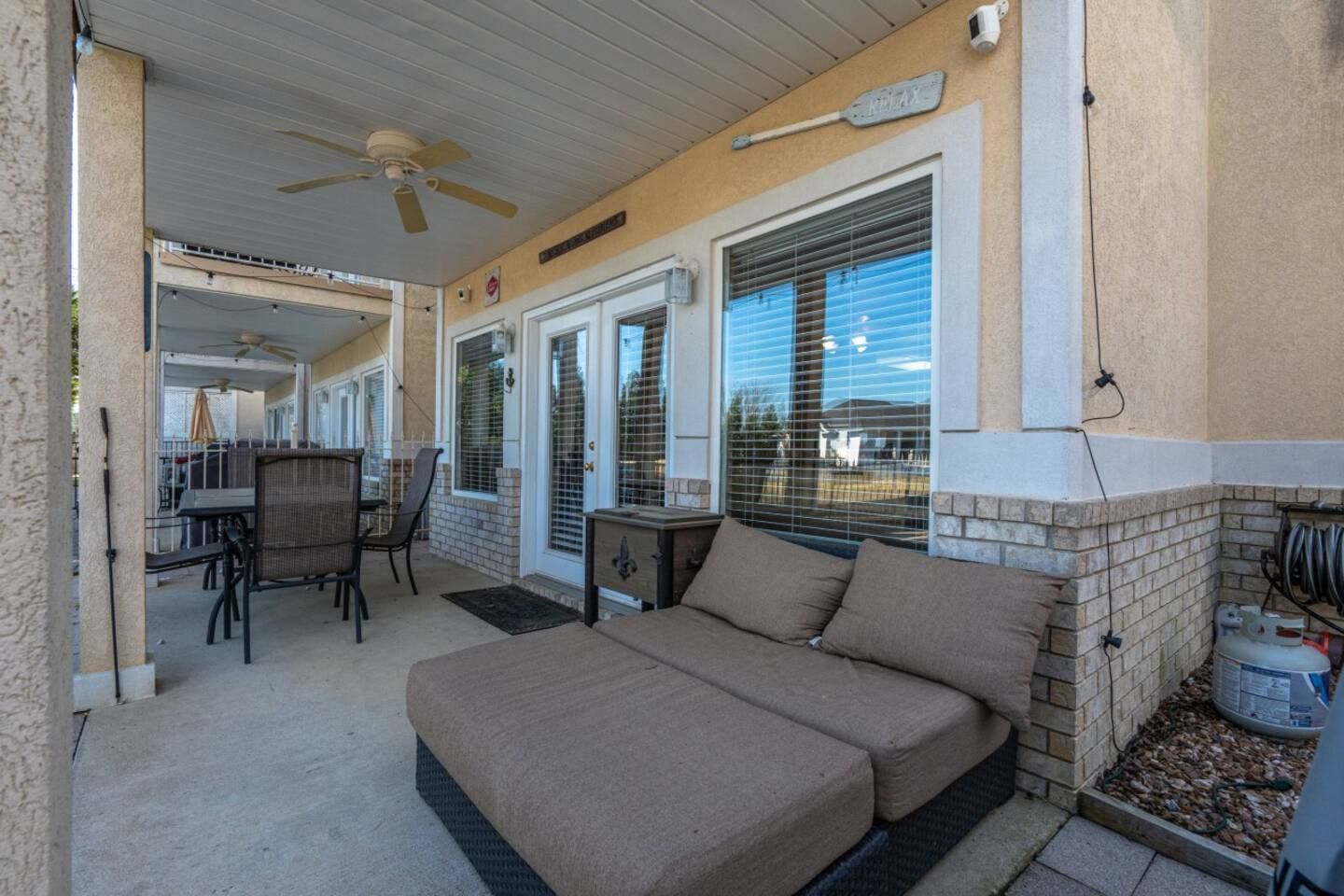 A patio with a couch , chairs , a table and a ceiling fan.