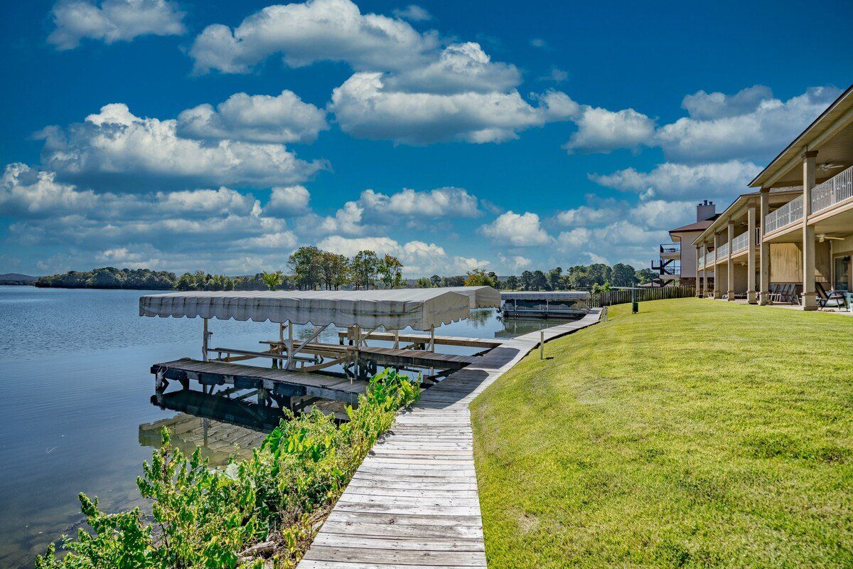 A wooden walkway leading to a dock next to a lake.