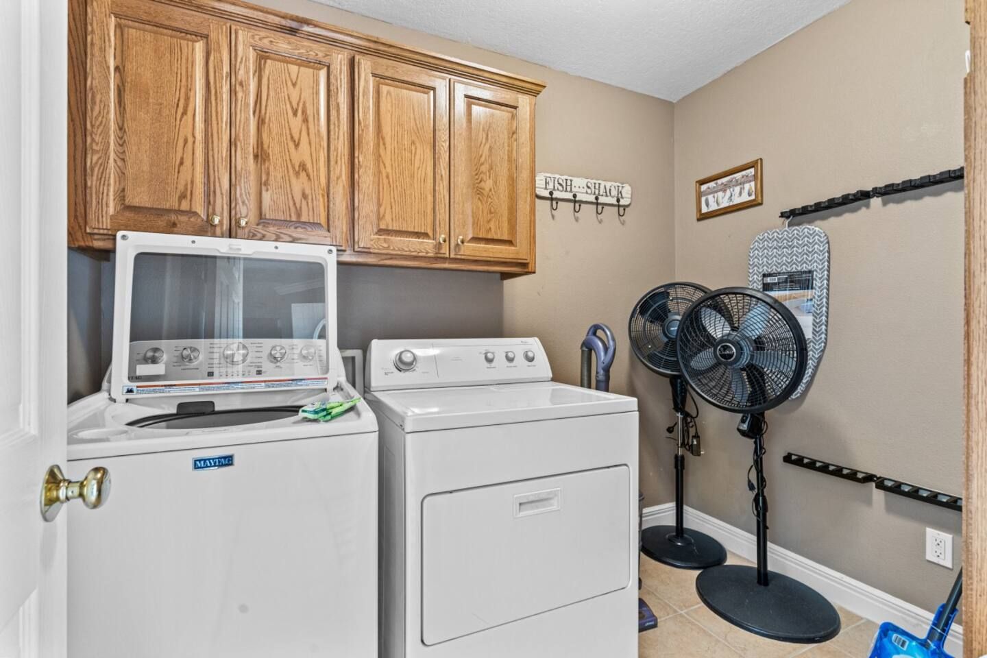 A laundry room with a washer and dryer and two fans.