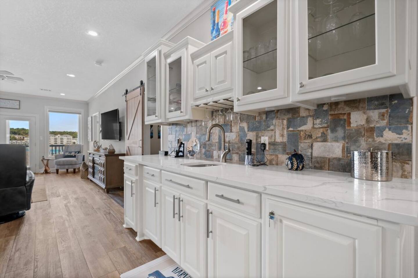 A kitchen with white cabinets , white counter tops , and a sink.