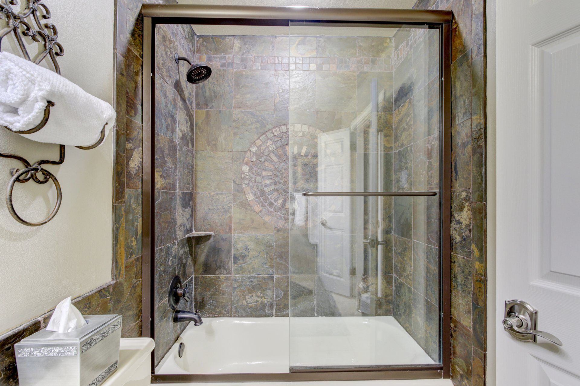 A bathroom with a tub and a shower with a sliding glass door.
