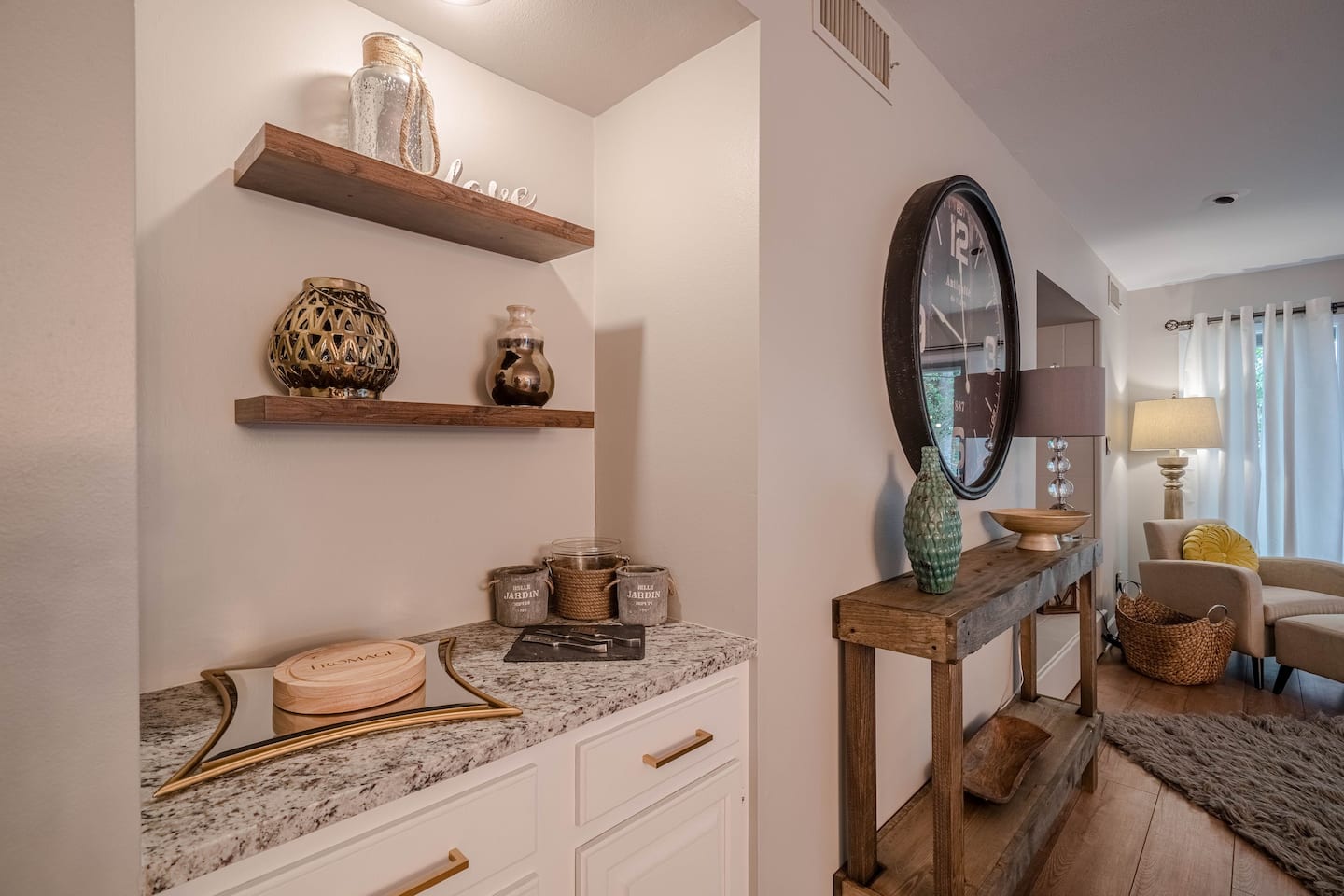 A living room with a table , shelves , and a mirror.
