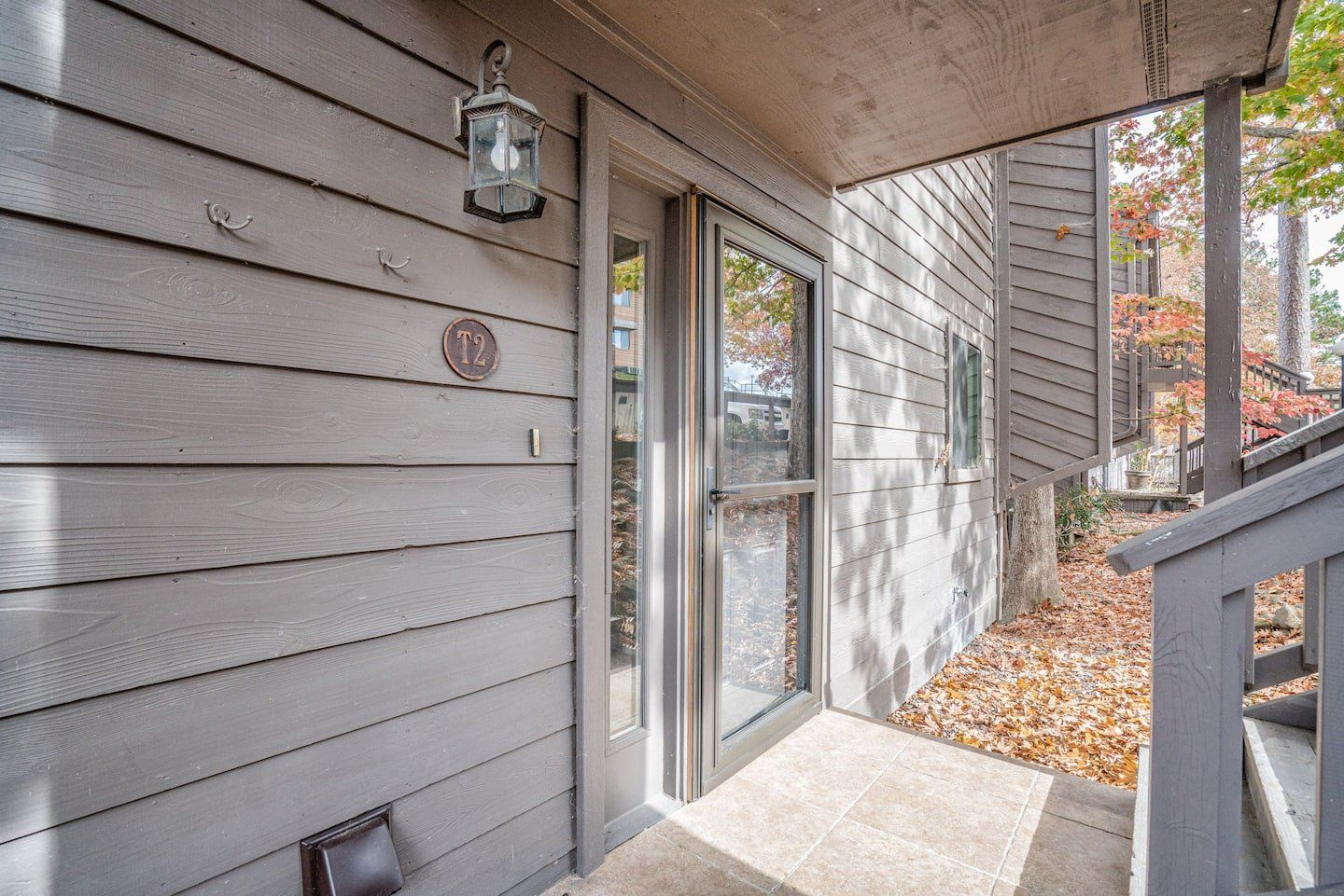 The front door of a house with a porch and stairs leading up to it.