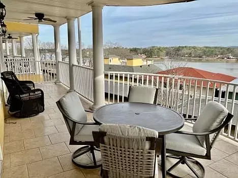 A balcony with a table and chairs overlooking a lake.