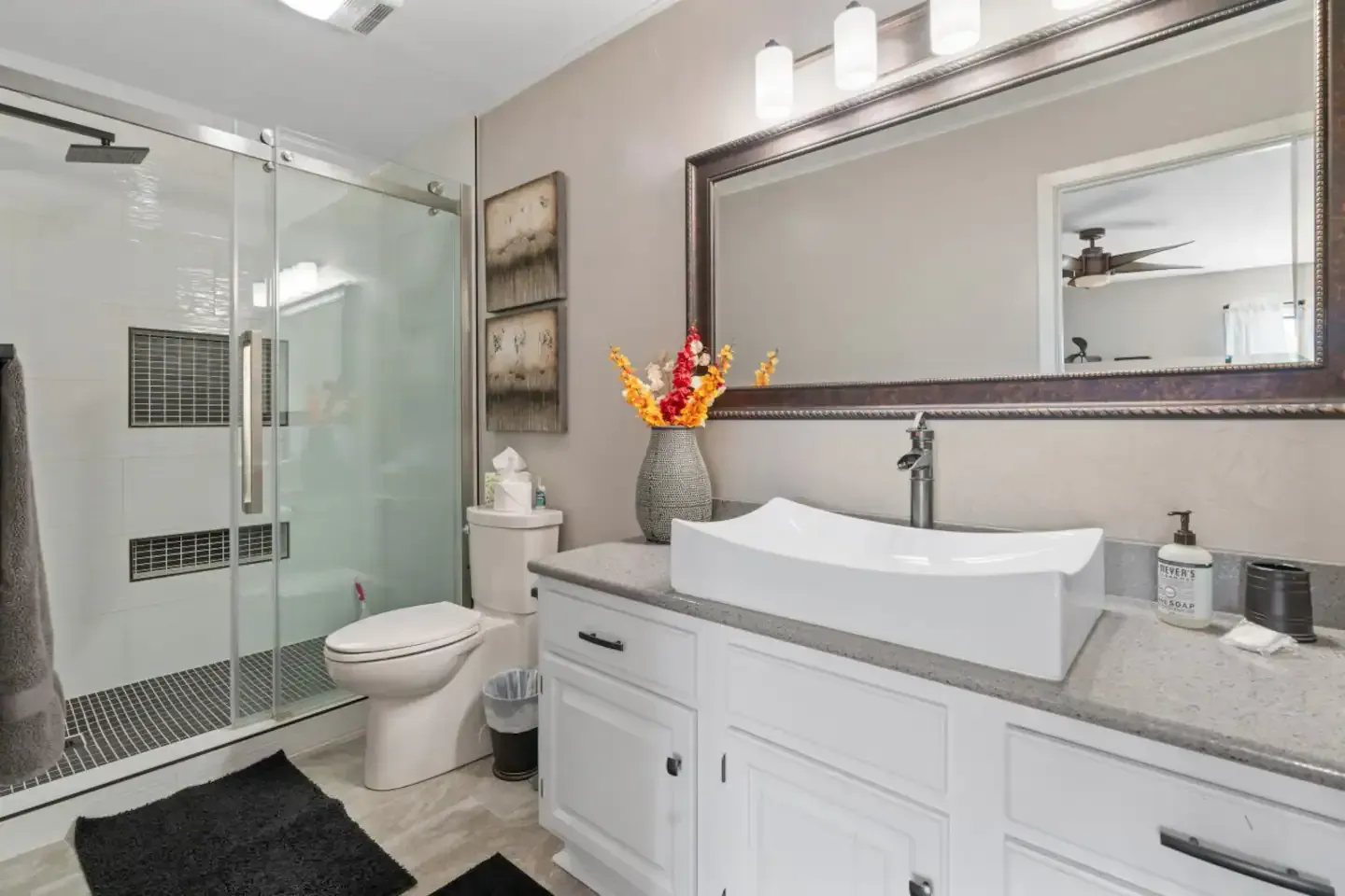A bathroom with a toilet , sink , mirror and shower.
