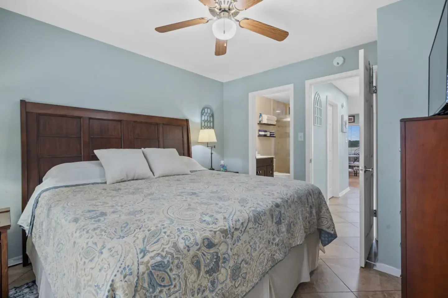 A bedroom with a king size bed and a ceiling fan.