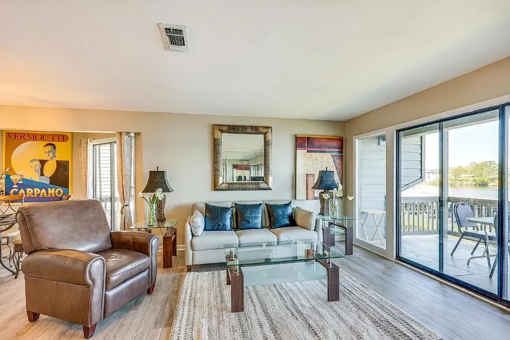 A living room with a couch , chair , coffee table and sliding glass doors.