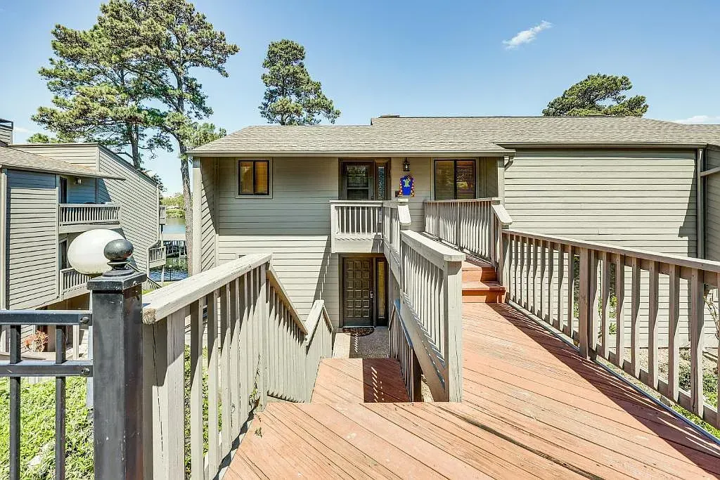 A house with a wooden deck and stairs leading up to it.