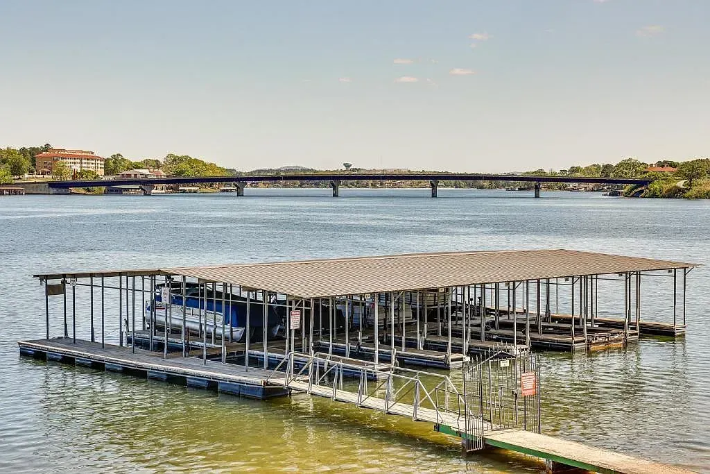 A dock filled with boats on a lake with a bridge in the background.