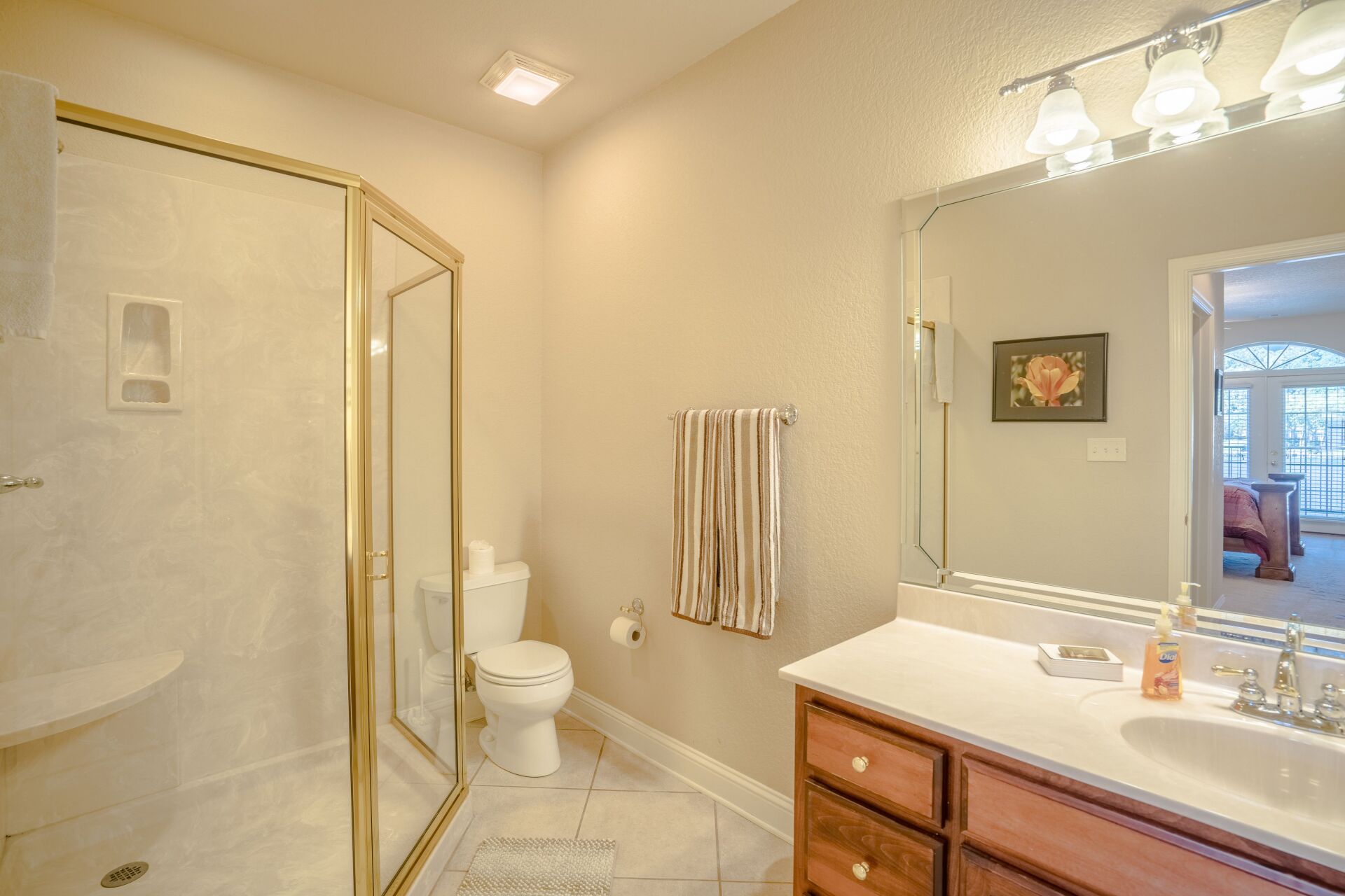A bathroom with a toilet , sink , mirror and walk in shower.